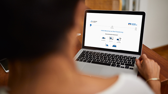 Person sitzt vor einem Laptop und betrachtet eine Finanzierungswebseite mit verschiedenen Auswahloptionen.